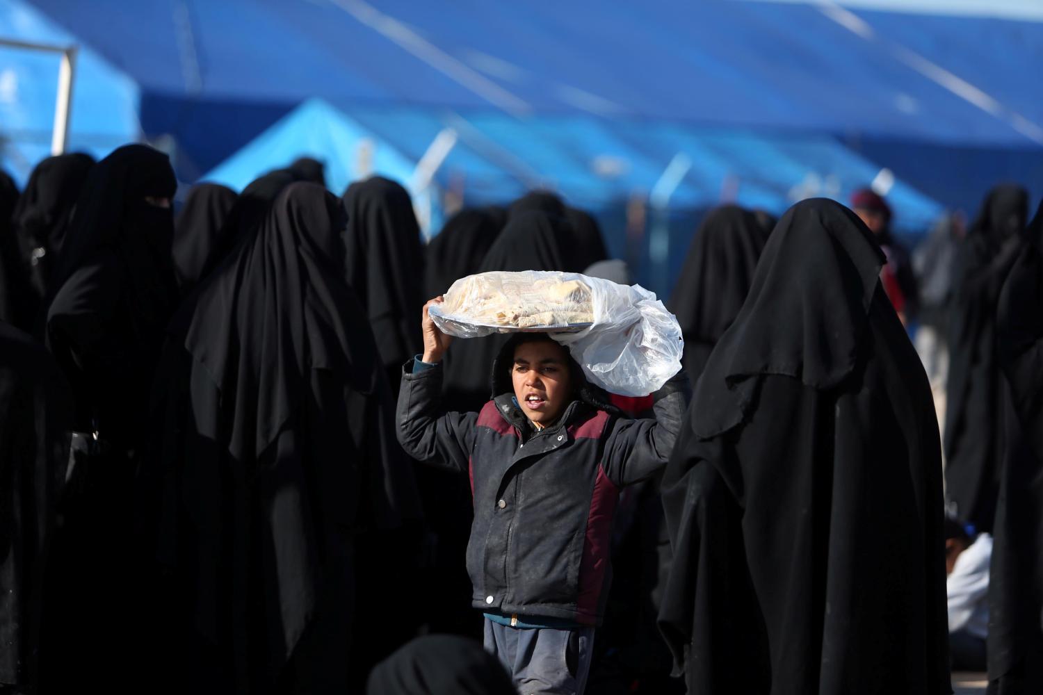 A boy carries bread on his head at al-Hol displacement camp in Hasaka governorate, Syria April 2, 2019. REUTERS/Ali Hashisho - RC1D6612CE50