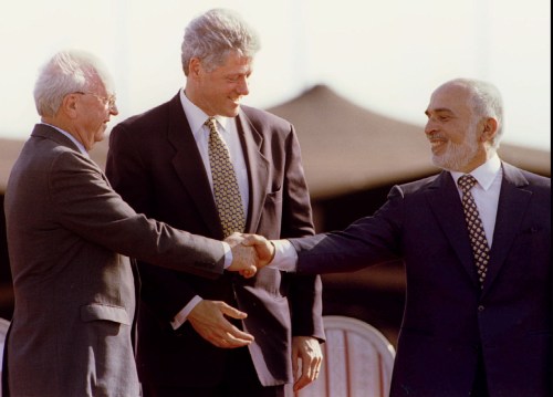 US President Bill Clinton applauds as Jordan s King Hussein reaches out and shakes hands with Israeli Prime Minister Yitzhak Rabin (L) at the end of the Israeli - Jordanian peace treaty signing ceremony - PBEAHUNIEEZ