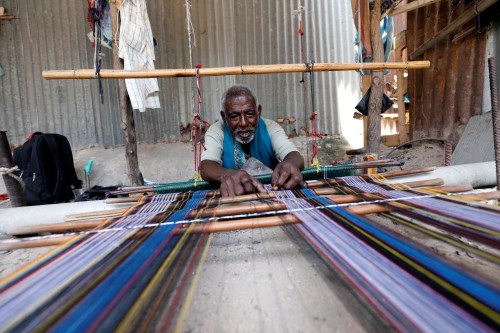 Abdulahi Abuker weaves threads into traditional garments, preserving a Somali tradition that is under threat from a flood of inexpensive clothes imported from China and other countries, in the Madina district of Mogadishu, Somalia.September 13, 2019.Picture taken September 13, 2019.  REUTERS/Feisal Omar - RC1156B19070