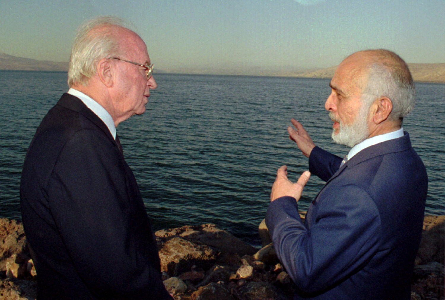 Jordan's King Hussein (R) and Israeli Prime Minister Yitzhak Rabin talk on the shore of the Sea of Galilee in Tzemach November 10, after exchanging ratified copies of the Israel-Jordan Peace Treaty - PBEAHUNIDCU