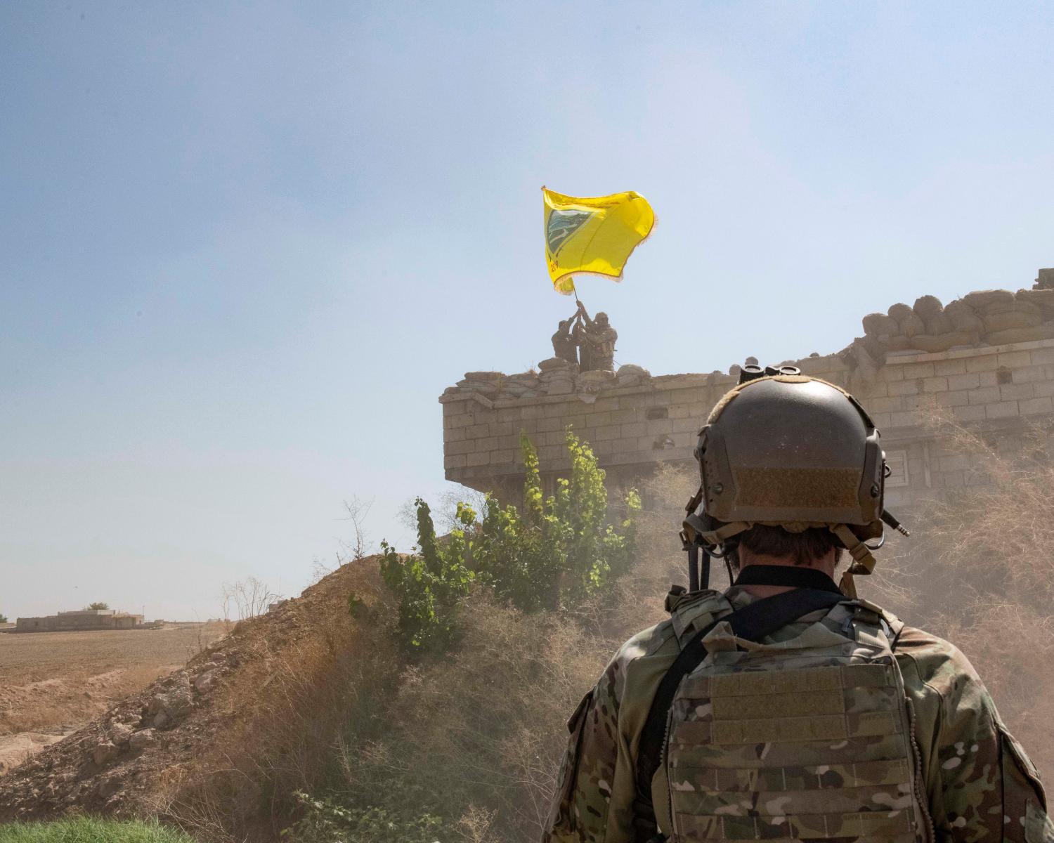 A U.S. soldier oversees members of the Syrian Democratic Forces as they demolish a YPG fortification and raise a Tal Abyad Military Council flag over the outpost as part of the security mechanism zone agreement, in Syria September 21, 2019.  Picture taken September 21, 2019.  U.S. Army/Staff Sgt. Andrew Goedl/Handout via REUTERS.  THIS IMAGE HAS BEEN SUPPLIED BY A THIRD PARTY. - RC1745C73700