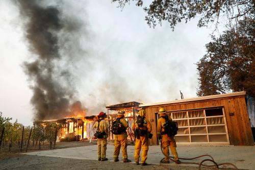 A group of firefighters look on as a house burns during the wind-driven Kincade Fire in Healdsburg, California, U.S. October 27, 2019. REUTERS/Stephen Lam - RC1CE4C5F940