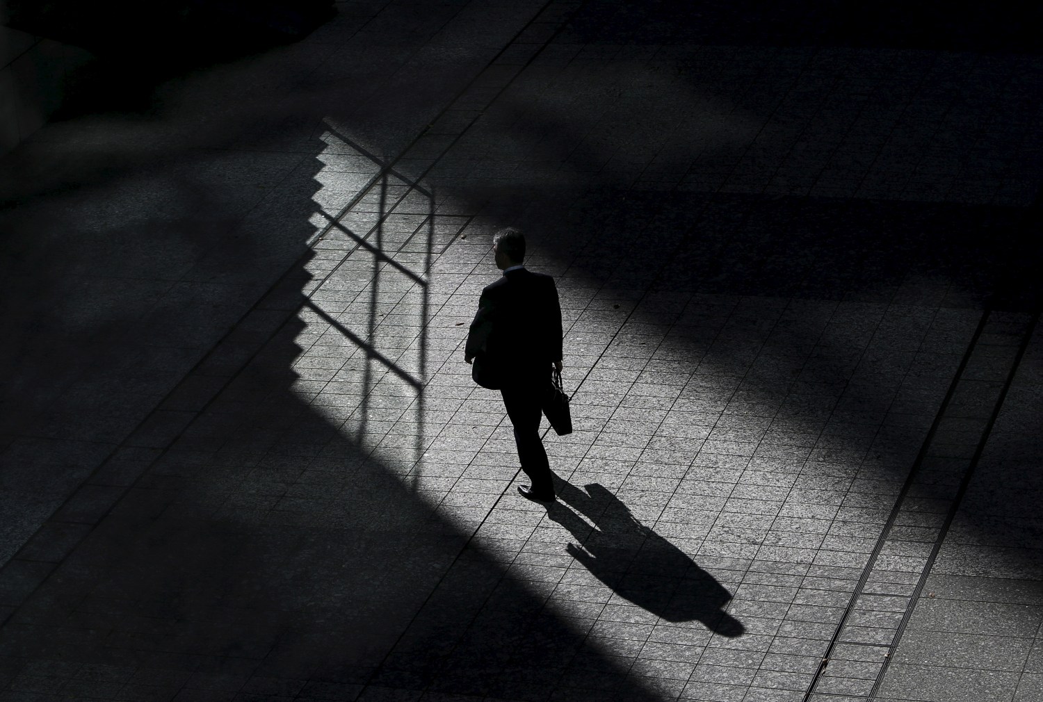 A man walks on a street between buildings at a business district in Tokyo, Japan, November 19, 2015. The Bank of Japan maintained its current pace of monetary stimulus on Thursday, clinging to hopes that an economic recovery is in sight despite soft domestic capital expenditure and challenging global business conditions. REUTERS/Yuya Shino - GF20000065409
