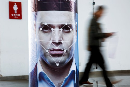 A man walks past a poster simulating facial recognition software at the Security China 2018 exhibition on public safety and security in Beijing, China October 24, 2018.   REUTERS/Thomas Peter - RC195B4D37A0