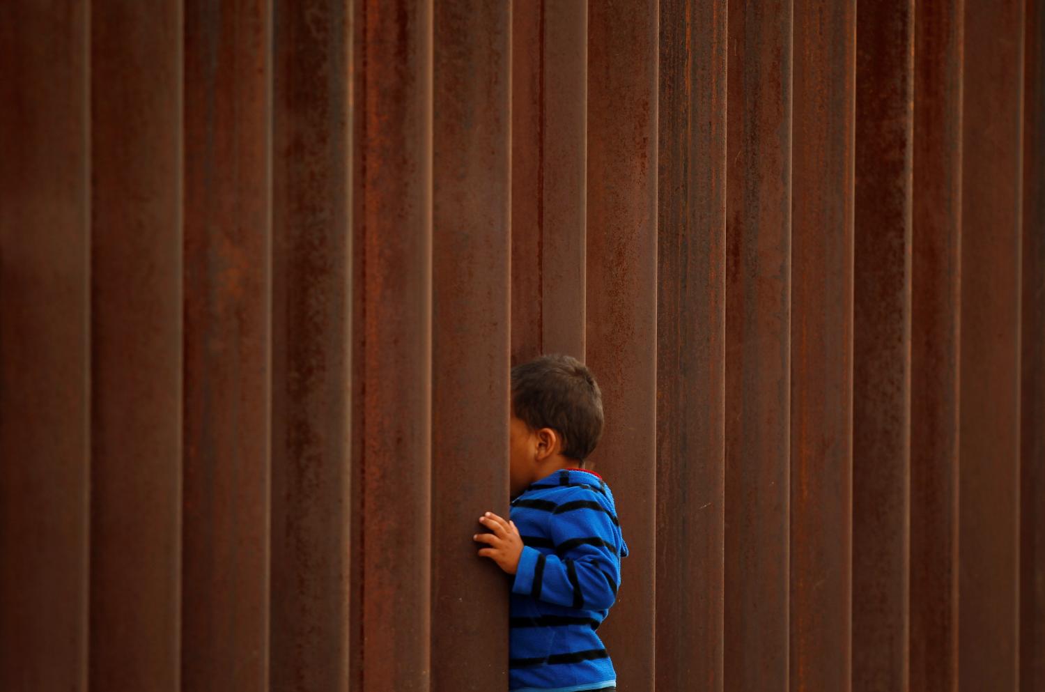 A child peeks through the border fence during the "Interfaith Service for Justice and Mercy at the Border" to demand the U.S. government to end the separation of immigrant children from their parents at the border, in Ciudad Juarez, Mexico September 7, 2018. REUTERS/Jose Luis Gonzalez - RC1410DF6D00