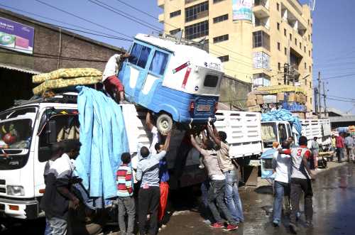 Labourers load a three-wheeled vehicle onto the back of a van at the Mercato market in Addis Ababa October 9, 2015. Addis Ababa's 'Mercato' - Italian for 'market' - is reputedly the biggest open-air market in Africa, lying in the west of the capital. Supermarkets have sprouted across the city as the metropolis has expanded with Ethiopia's booming economy, but Mercato remains a popular destination for shoppers seeking clothing, electronics and a huge range of other items. It has been around for as long as the city, which was founded at the end of the 19th century, but it took its current form, and its name, from the Italians who invaded Ethiopia in 1935. The Italian occupation ended in 1941. Picture taken October 9, 2015.    REUTERS/Tiksa Negeri  - GF10000267957