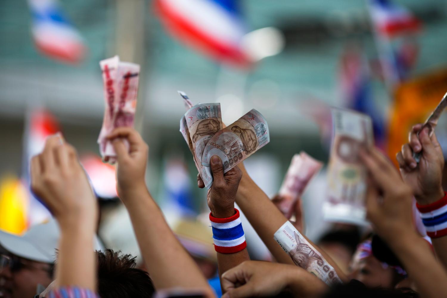 Anti-government protesters hold money to donate to protest leader Suthep Thaugsuban as he leads thousands of protesters in a march in central Bangkok January 19, 2014. Twenty-eight people were injured, seven of them seriously, in an explosion on Sunday at a camp of anti-government protesters in the center of the Thai capital, medical officials said. REUTERS/Athit Perawongmetha (THAILAND - Tags: POLITICS CIVIL UNREST) - GM1EA1J1C4C01