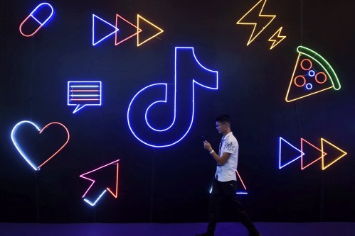 A man holding a phone walks past a sign of Chinese company ByteDance's app TikTok, known locally as Douyin, at the International Artificial Products Expo in Hangzhou, Zhejiang province, China October 18, 2019. Picture taken October 18, 2019.  REUTERS/Stringer  ATTENTION EDITORS - THIS IMAGE WAS PROVIDED BY A THIRD PARTY. CHINA OUT. - RC171198B320