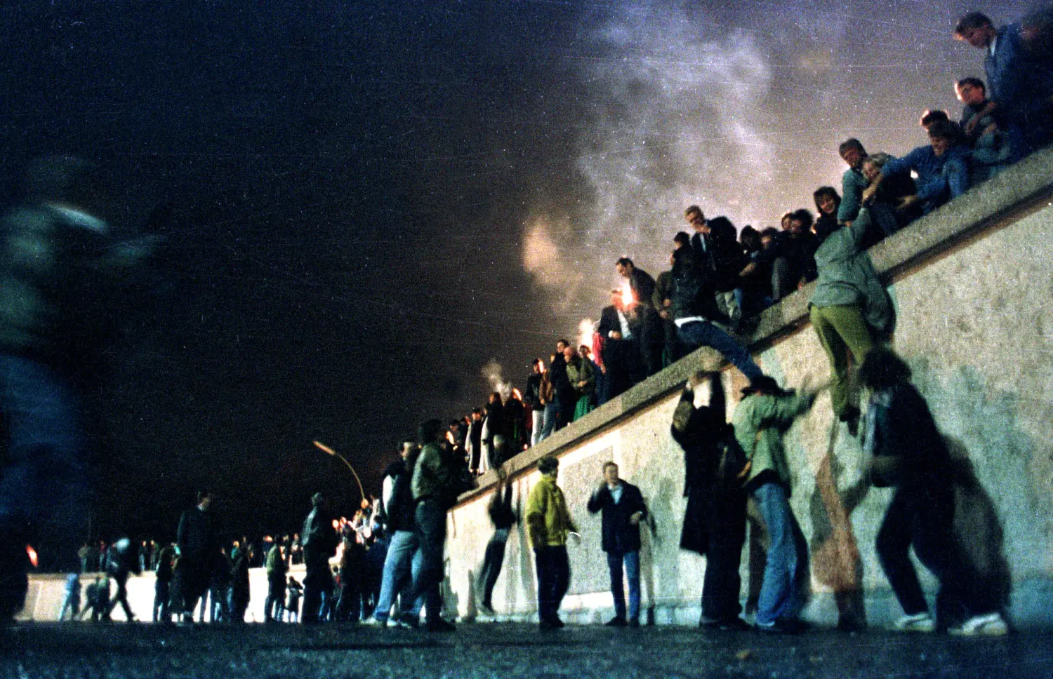 People climb the Berlin Wall at the Brandenburg Gate after the opening of the East German border November 9, 1989. REUTERS/Herbert Knosowski - RP1DRILJKDAA