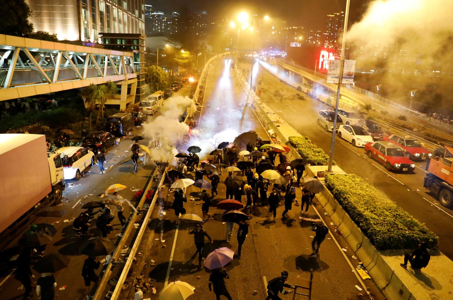 Anti-government demonstrators take cover during clashes with police near the Hong Kong Polytechnic University (PolyU) in Hong Kong, China November 18, 2019. REUTERS/Adnan Abidi - RC2TDD9TCYYS