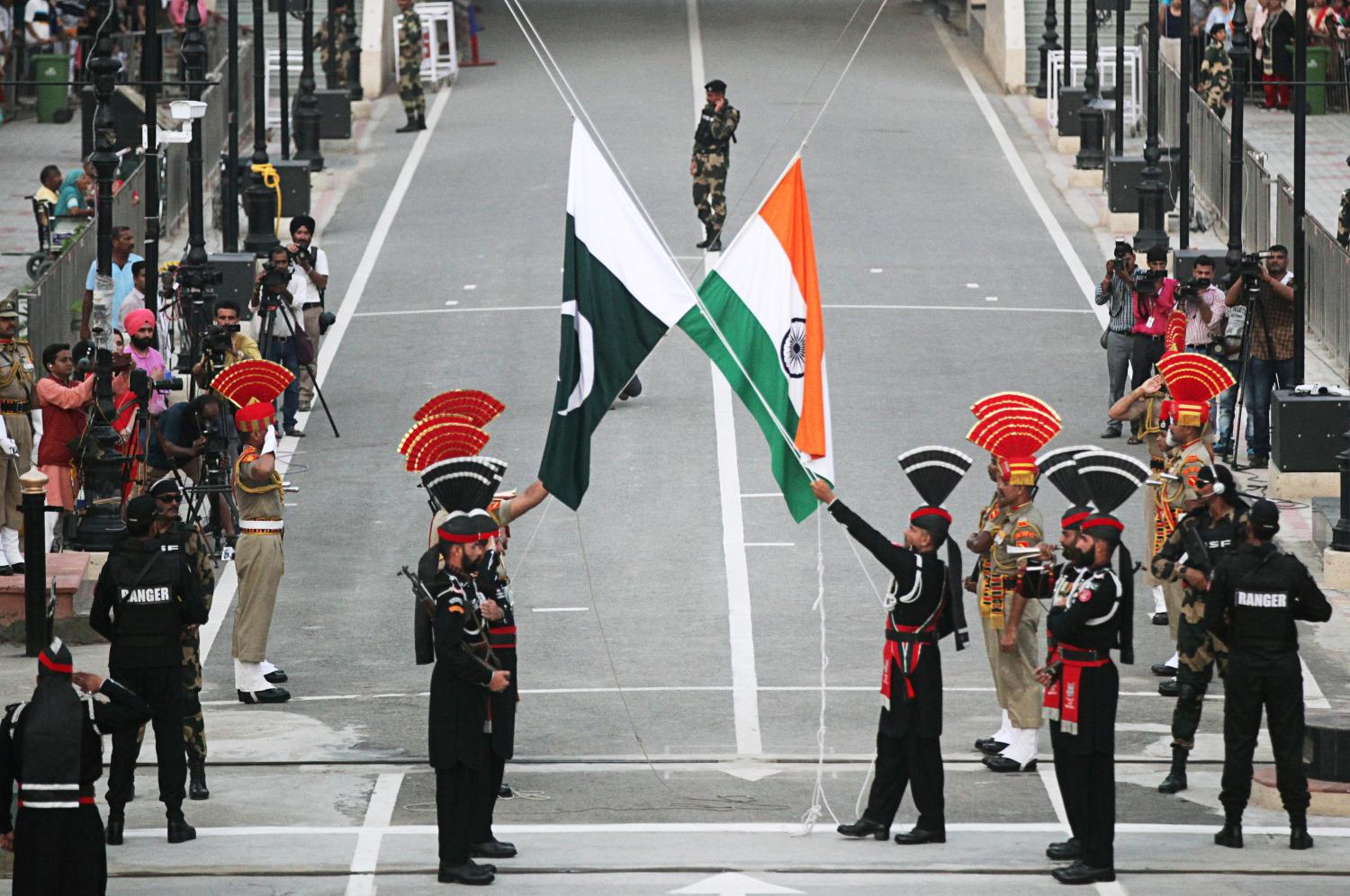 Pakistani Rangers (wearing black uniforms) and Indian Border Security Force (BSF) officers lower their national flags during parade on the Pakistan's 72nd Independence Day, at the Pakistan-India joint check-post at Wagah border, near Lahore, Pakistan August 14, 2019. REUTERS/Mohsin Raza - RC14044E1270