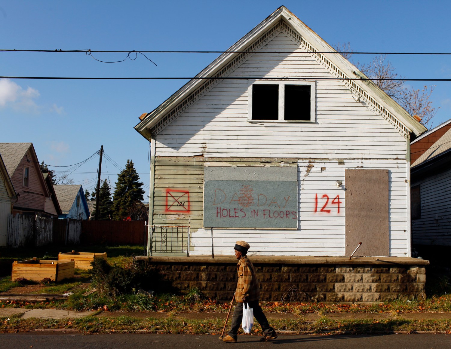 A man walks past an empty house marked for demolition in the Broadway-Fillmore neighborhood of Buffalo, New York, November 20, 2009.  Buffalo has 15,000 vacant lots from houses that have been demolished, amounting to 3200 acres of vacant land.   REUTERS/Brian Snyder    (UNITED STATES BUSINESS SOCIETY)