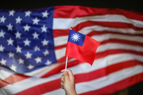 An anti-government protester holds a Taiwan national flag as an U.S. flag flutters in the background during a demonstration to celebrate Taiwan's National Day at the Harbour city in Tsim Sha Tsui district, in Hong Kong, China October 10, 2019. REUTERS/Athit Perawongmetha - RC19205F0000