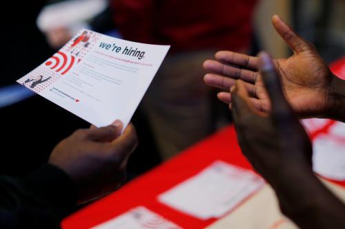 A job seeker holds a "We're Hiring" card while talking to a representative from Target at a City of Boston Neighborhood Career Fair on May Day in Boston, Massachusetts, U.S., May 1, 2017.   REUTERS/Brian Snyder - RC1B6FFBEDC0