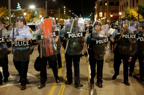 Police officers watch as people march the day after the not guilty verdict in the murder trial of Jason Stockley, a former St. Louis police officer, charged with the 2011 shooting of Anthony Lamar Smith, who was black, in St. Louis, Missouri, U.S., September 16, 2017. REUTERS/Joshua Lott - RC1B6E82D250