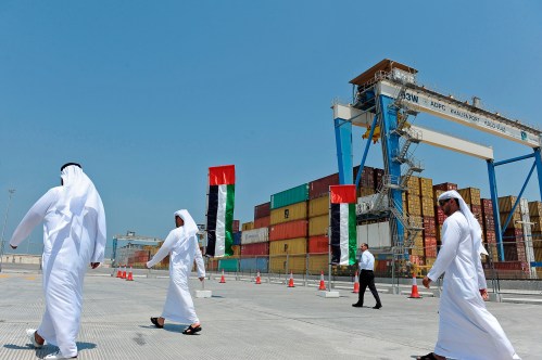 People walk past containers in Khalifa Port during its opening in Taweelah, Abu Dhabi September 1, 2012. Abu Dhabi launched operations at a multi-billion dollar port facility on Saturday, seeking to diversify its oil-based economy with a project that could intensify competition for the region's shipping traffic with neighbouring emirate Dubai. Abu Dhabi Ports Co (ADPC) said Khalifa Port, built on a man-made island in the Taweelah area, and its adjacent Khalifa Industrial Zone would together be two-thirds the size of Singapore when fully built. REUTERS/Ben Job (UNITED ARAB EMIRATES - Tags: MARITIME BUSINESS)