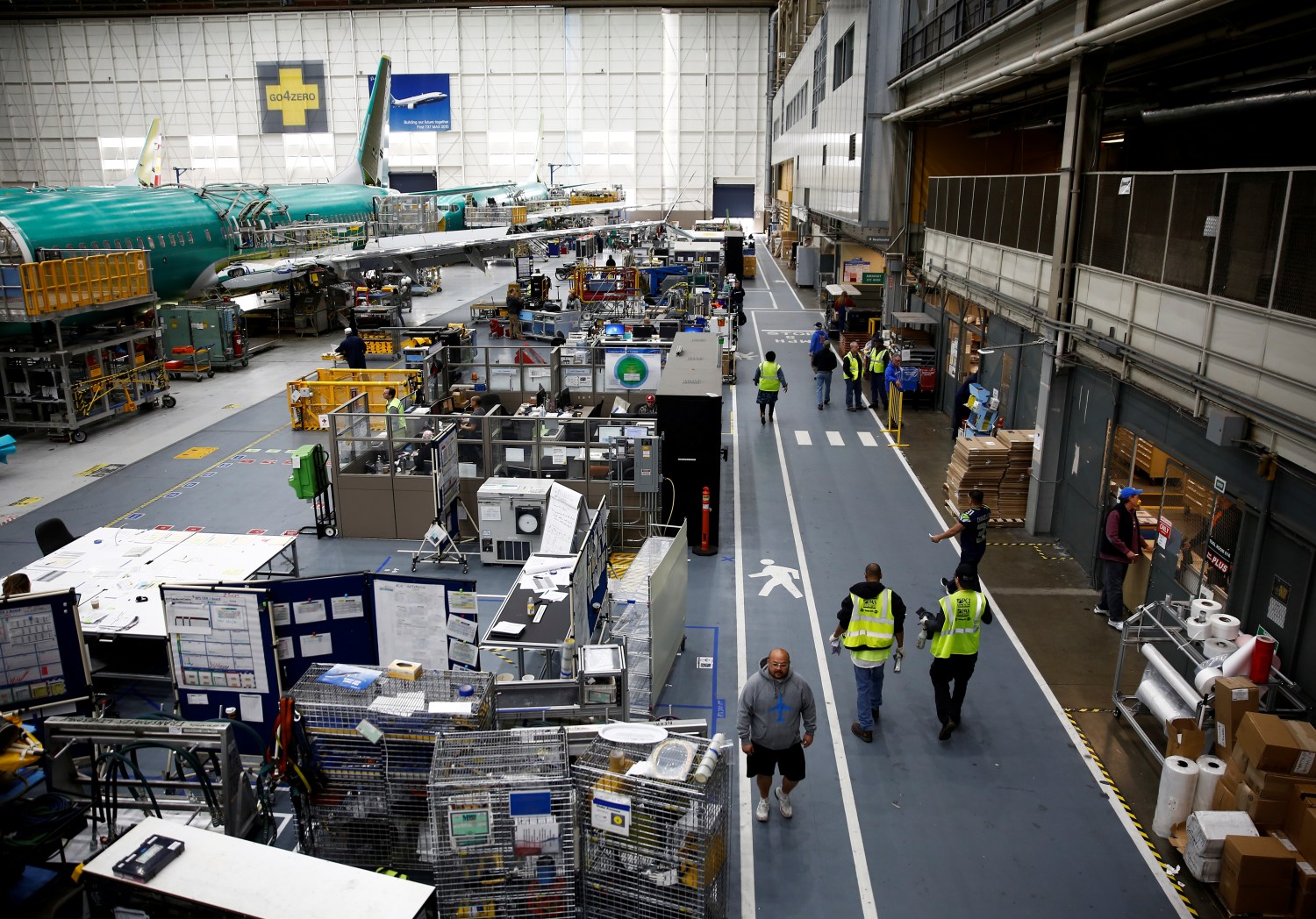 Workers walk by a 737 Max aircraft on the production line at the Boeing factory in Renton, Washington, U.S., March 27, 2019.  REUTERS/Lindsey Wasson