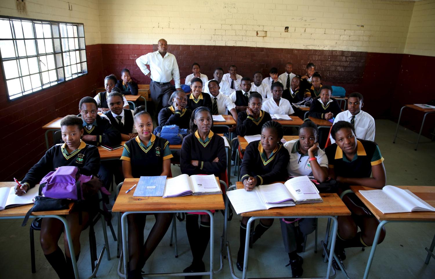 Teacher Reginald Sikhwari poses for a picture with his class of grade 11 students at Sekano-Ntoane school in Soweto, South Africa, September 17, 2015. Nearly three years after Taliban gunmen shot Pakistani schoolgirl Malala Yousafzai, the teenage activist last week urged world leaders gathered in New York to help millions more children go to school. World Teachers' Day falls on 5 October, a Unesco initiative highlighting the work of educators struggling to teach children amid intimidation in Pakistan, conflict in Syria or poverty in Vietnam. Even so, there have been some improvements: the number of children not attending primary school has plummeted to an estimated 57 million worldwide in 2015, the U.N. says, down from 100 million 15 years ago. Reuters photographers have documented learning around the world, from well-resourced schools to pupils crammed into corridors in the Philippines, on boats in Brazil or in crowded classrooms in Burundi. REUTERS/Siphiwe Sibeko PICTURE 39 OF 47 FOR WIDER IMAGE STORY "SCHOOLS AROUND THE WORLD"SEARCH "EDUCATORS SCHOOLS" FOR ALL IMAGES