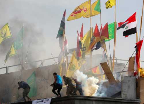 Protesters and militia fighters run away from tear gas thrown by U.S. Embassy security men, during a protest to condemn air strikes on bases belonging to Hashd al-Shaabi (paramilitary forces), outside the embassy in Baghdad, Iraq January 1, 2020. REUTERS/Thaier al-Sudani