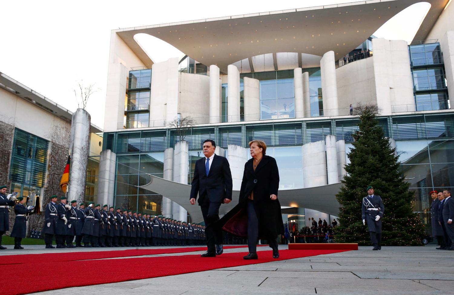 German Chancellor Angela Merkel and Libyan Prime Minister Fayez al-Sarraj walk during a welcome ceremony at the Chancellery in Berlin, Germany, December 7, 2017. REUTERS/Fabrizio Bensch - RC184FAC1510