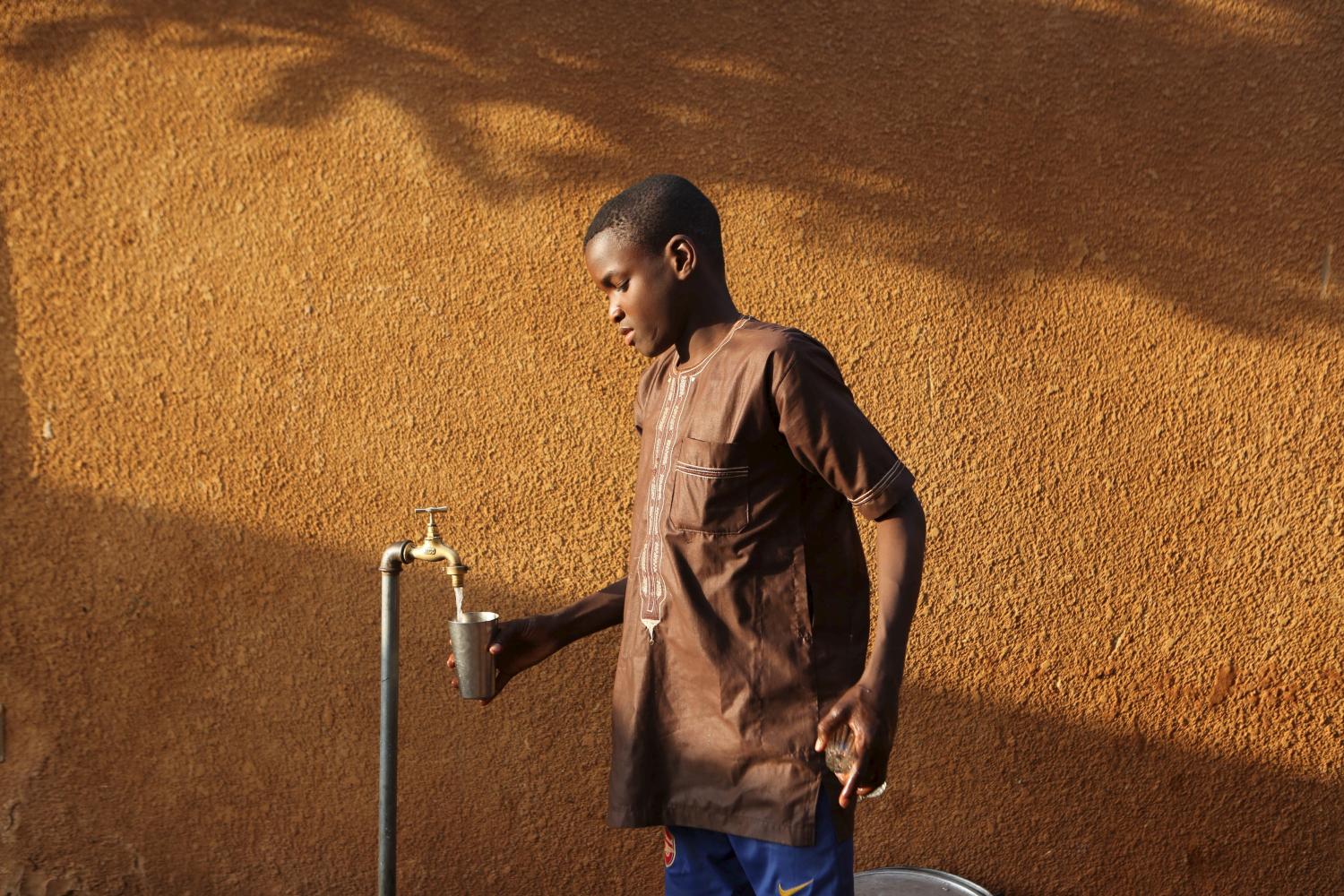 A boy gets water to make tea in Niamey, Niger, February 16, 2016.  REUTERS/Joe Penney - GF10000311386