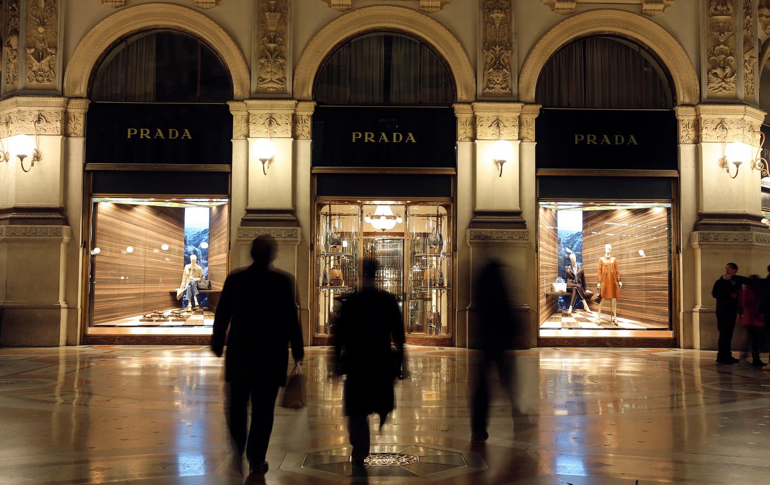 People walk past Prada's fashion store in downtown Milan February 4, 2015. The trend in luxury goods is to drum up same store sales by curbing expansion and wowing customers with new products, yet Prada continues to pay over the odds to open swanky new shops and stock them with handbags little changed from previous bestsellers. Prada, say analysts, now urgently needs to focus less on new stores and more on new handbags. Picture taken February 4. To match Analysis PRADA-STRATEGY/       REUTERS/Stefano Rellandini (ITALY - Tags: BUSINESS FASHION)