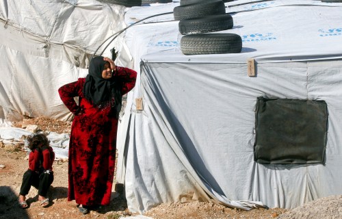 FILE PHOTO: A Syrian refugee woman stands outside a tent at a camp in Bar Elias, in the Bekaa Valley, Lebanon January 13, 2020. Picture taken January 13, 2020. REUTERS/Mohamed Azakir/File Photo