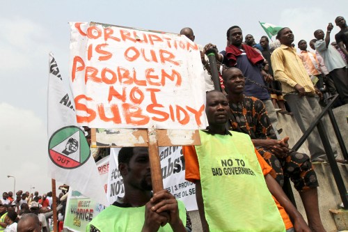 A protester holds up a placard at Gani Fawehinmi square during a protest against a fuel subsidy removal in Lagos January 9, 2012. Police shot dead one protester and wounded nearly two dozen as thousands of Nigerians demonstrated against the axing of fuel subsidies in Africa's top oil producing nation on Monday and unions launched an indefinite nationwide strike. REUTERS/Akintunde Akinleye(NIGERIA - Tags: CIVIL UNREST POLITICS ENERGY BUSINESS)