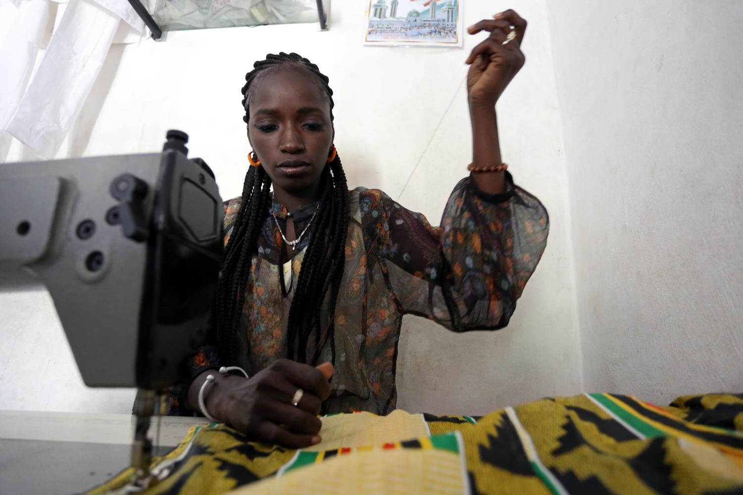 Fatou Kine works on a customer's order on a sewing machine purchased with money from the International Organization for Migration (IOM) in her shop in Guediawaye, Senegal April 16, 2018. Picture taken April 16, 2018.  To match Feature EUROPE-MIGRANTS/AFRICA   REUTERS/Mikal McAllister