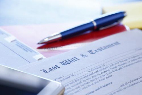 A ballpoint pen and a mobile phone rest on top of a last will and testament document that is part of the estate planning process.  This image is photographed using a very shallow depth of field.