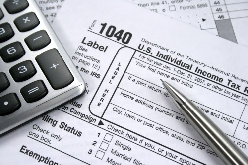 A 1040 Individual tax form with calculator and pencil.