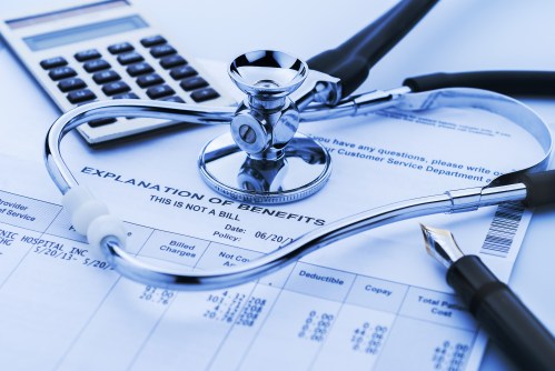 A stethoscope rests atop medical bills