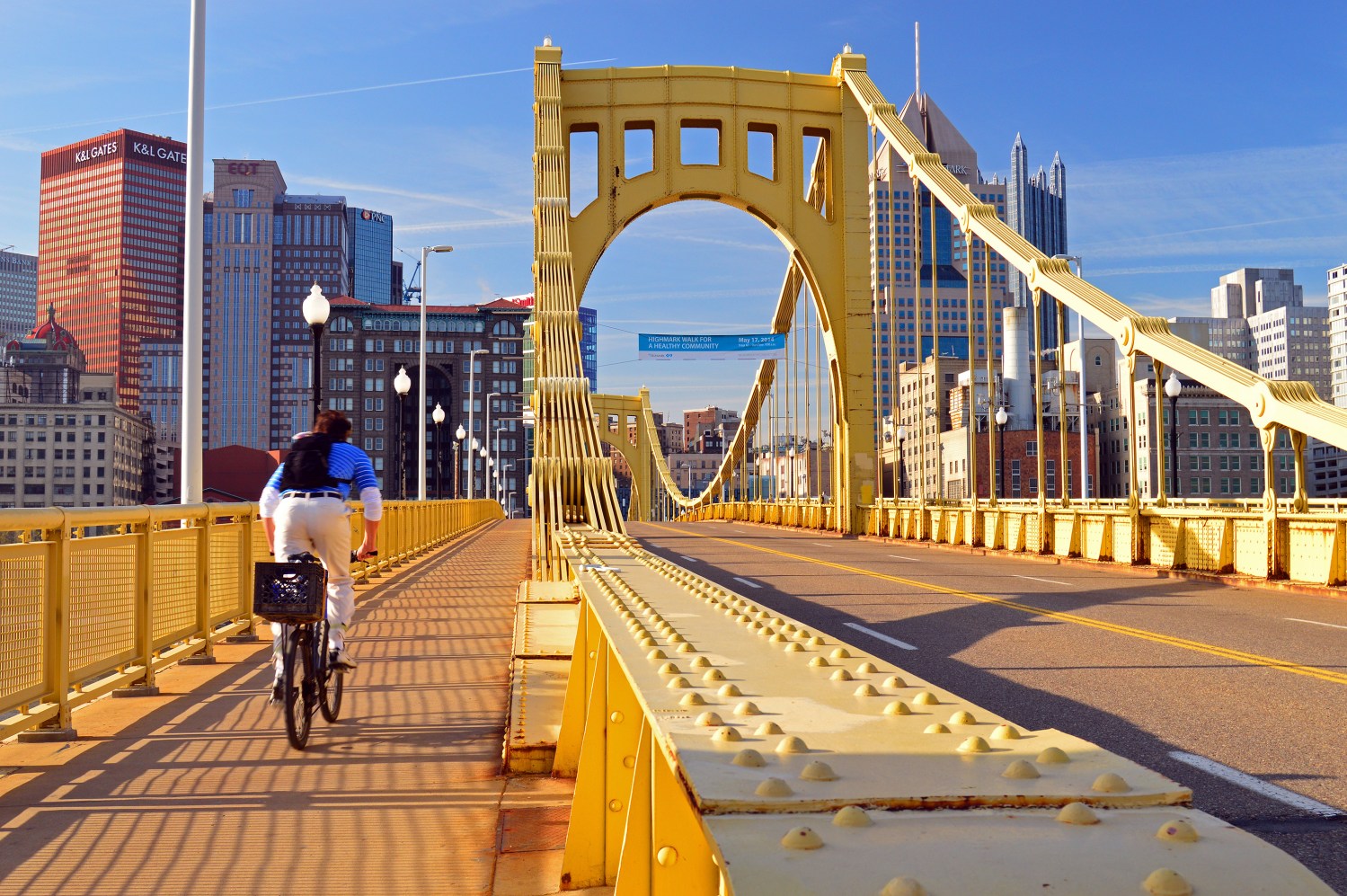 A young adult man bikes to work on the Roberto Clemente Bridge in Pittsburgh, Pennsylvania
