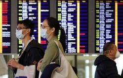 Passengers wear protective masks as they walk past an information board at Hong Kong International Airport, following the coronavirus outbreak in Hong Kong, China,