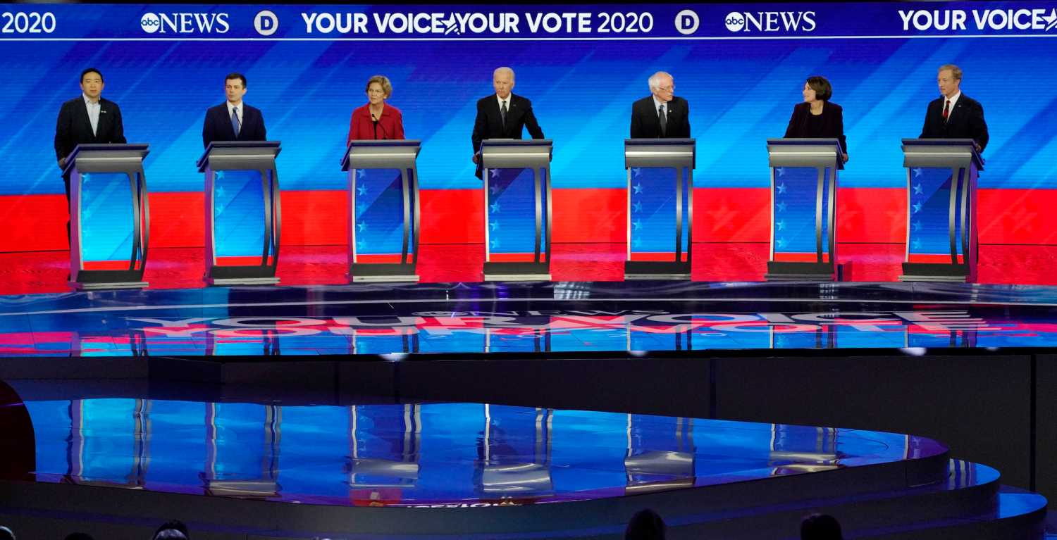 Democratic 2020 U.S. presidential candidates entrepreneur Andrew Yang, former South Bend Mayor Pete Buttigieg, Senator Elizabeth Warren, former Vice President Joe Biden, Senator Bernie Sanders, Senator Amy Klobuchar and billionaire activist Tom Steyer look on as audience members stand in support of Lt. Col. Alexander Vindman after a request from former Vice President Biden during the eighth Democratic 2020 presidential debate at Saint Anselm College in Manchester, New Hampshire, U.S., February 7, 2020. REUTERS/Brian Snyder