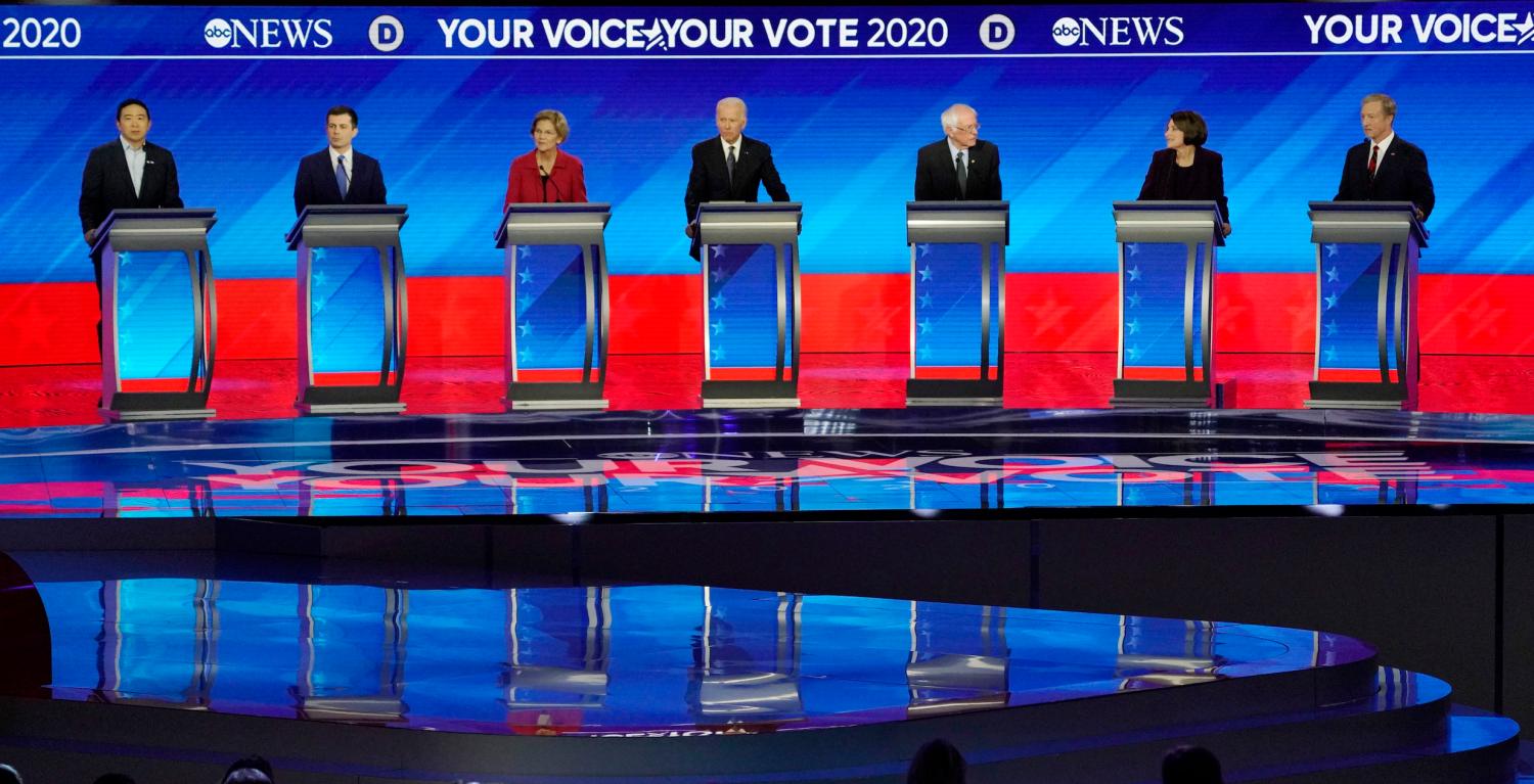 Democratic 2020 U.S. presidential candidates entrepreneur Andrew Yang, former South Bend Mayor Pete Buttigieg, Senator Elizabeth Warren, former Vice President Joe Biden, Senator Bernie Sanders, Senator Amy Klobuchar and billionaire activist Tom Steyer look on as audience members stand in support of Lt. Col. Alexander Vindman after a request from former Vice President Biden during the eighth Democratic 2020 presidential debate at Saint Anselm College in Manchester, New Hampshire, U.S., February 7, 2020. REUTERS/Brian Snyder