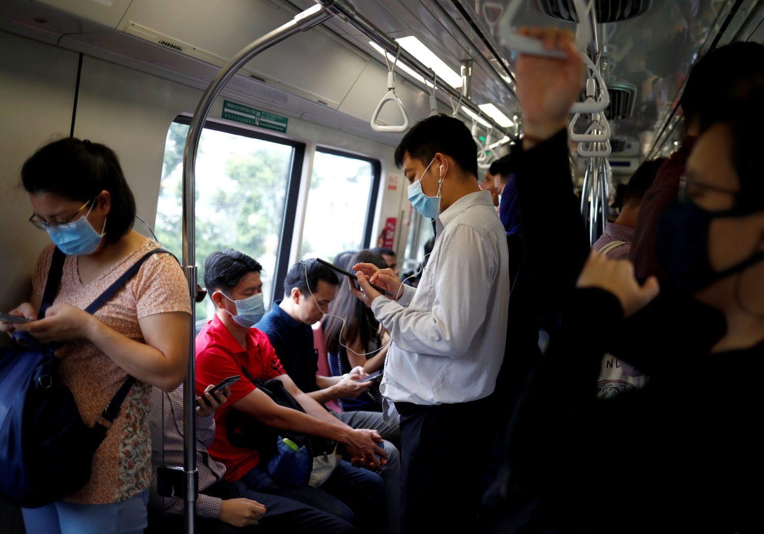 Commuters wearing masks in precaution of the coronavirus outbreak are pictured in a train during their morning commute in Singapore February 18, 2020. REUTERS/Edgar Su