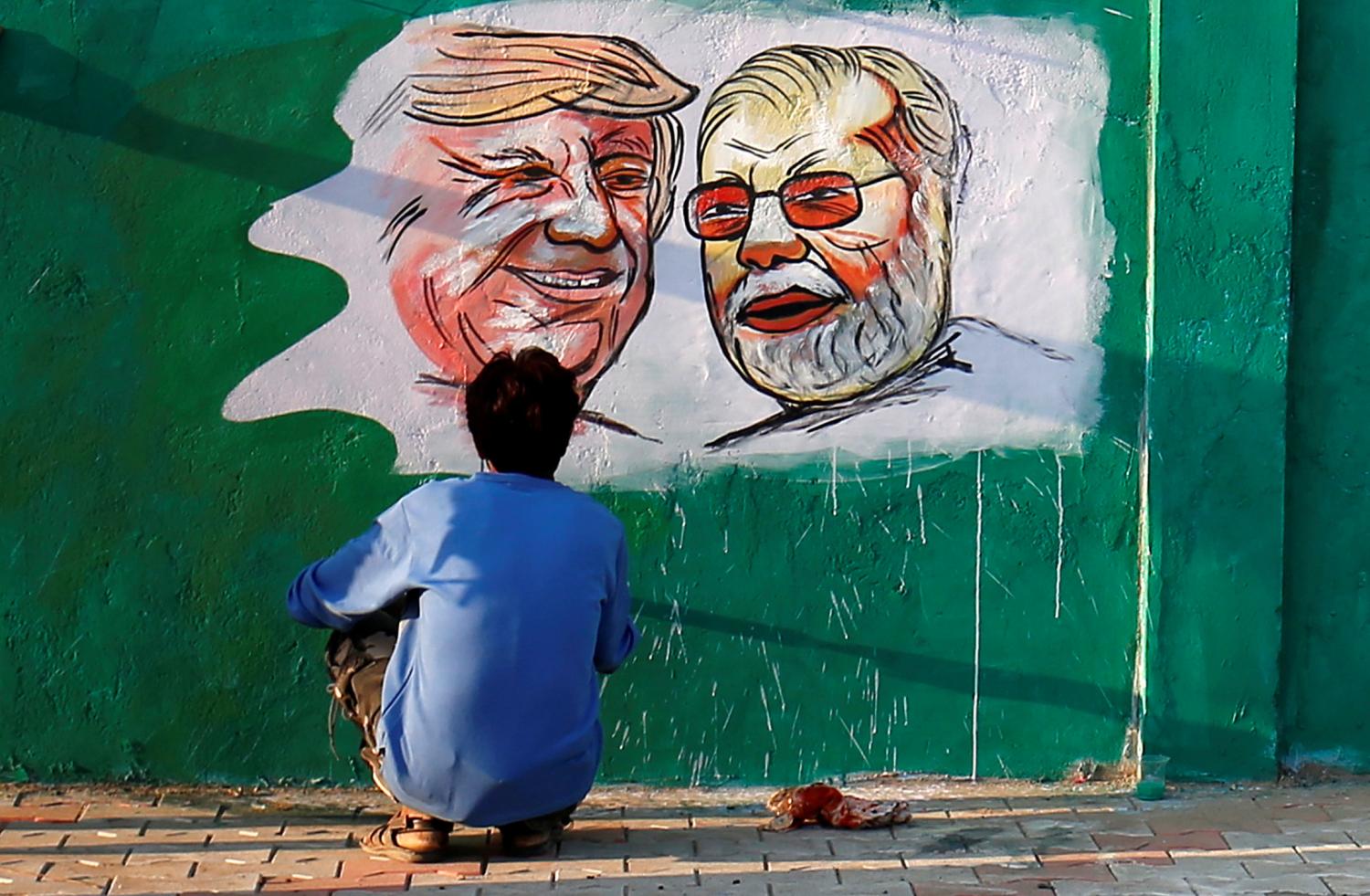 A man applies finishing touches to paintings of U.S. President Donald Trump and India's Prime Minister Narendra Modi on a wall as part of a beautification along a route that Trump and Modi will be taking during Trump's upcoming visit, in Ahmedabad, India, February 17, 2020. REUTERS/Amit Dave - RC2E2F9D35NB