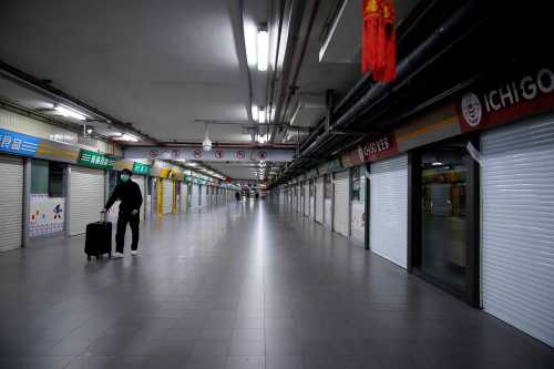 A man wearing a mask walks through closed stores in Shanghai, China, as the country is hit by an outbreak of a new coronavirus, February 4, 2020. REUTERS/Aly Song