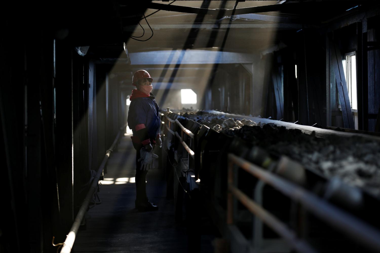 A worker inspects a conveyor belt carrying coal at a coal coking plant in Yuncheng, Shanxi province, China January 31, 2018. Picture taken January 31, 2018.  REUTERS/William Hong