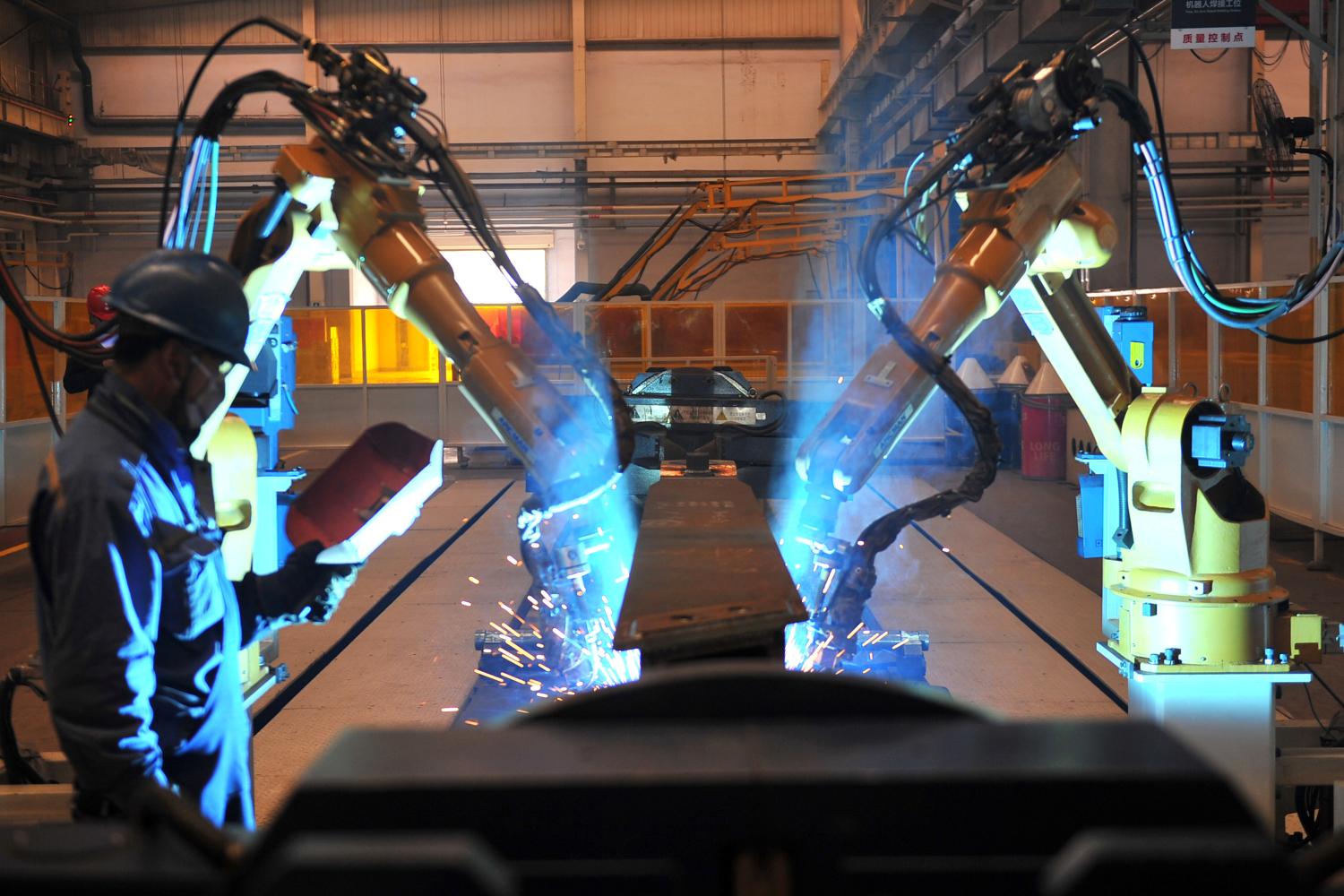 A worker stands next to robotic arms welding pump truck part at a factory of the Foton Loxa Heavy Machinery Co in Zhangjiakou, Hebei province, China May 24, 2019.  REUTERS/Stringer ATTENTION EDITORS - THIS IMAGE WAS PROVIDED BY A THIRD PARTY. CHINA OUT.