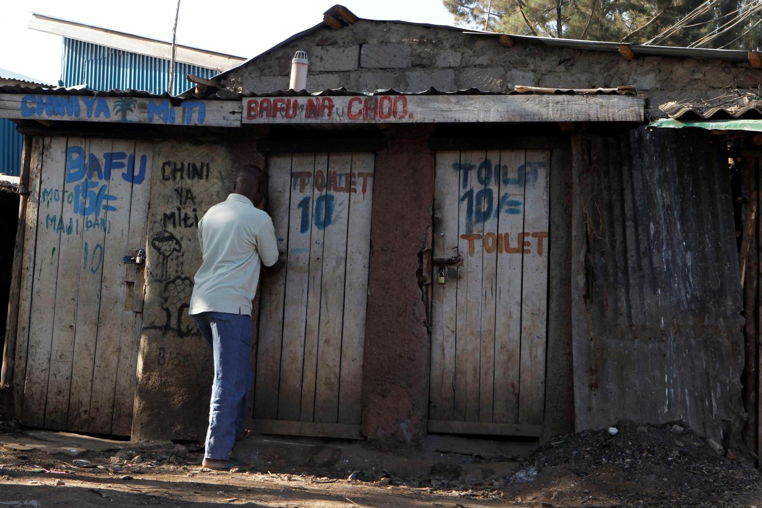 A slum dweller opens the door of a pay pit latrine in Kibera slum within Nairobi, Kenya February 27, 2019. Picture taken February 27, 2019. REUTERS/Njeri Mwangi