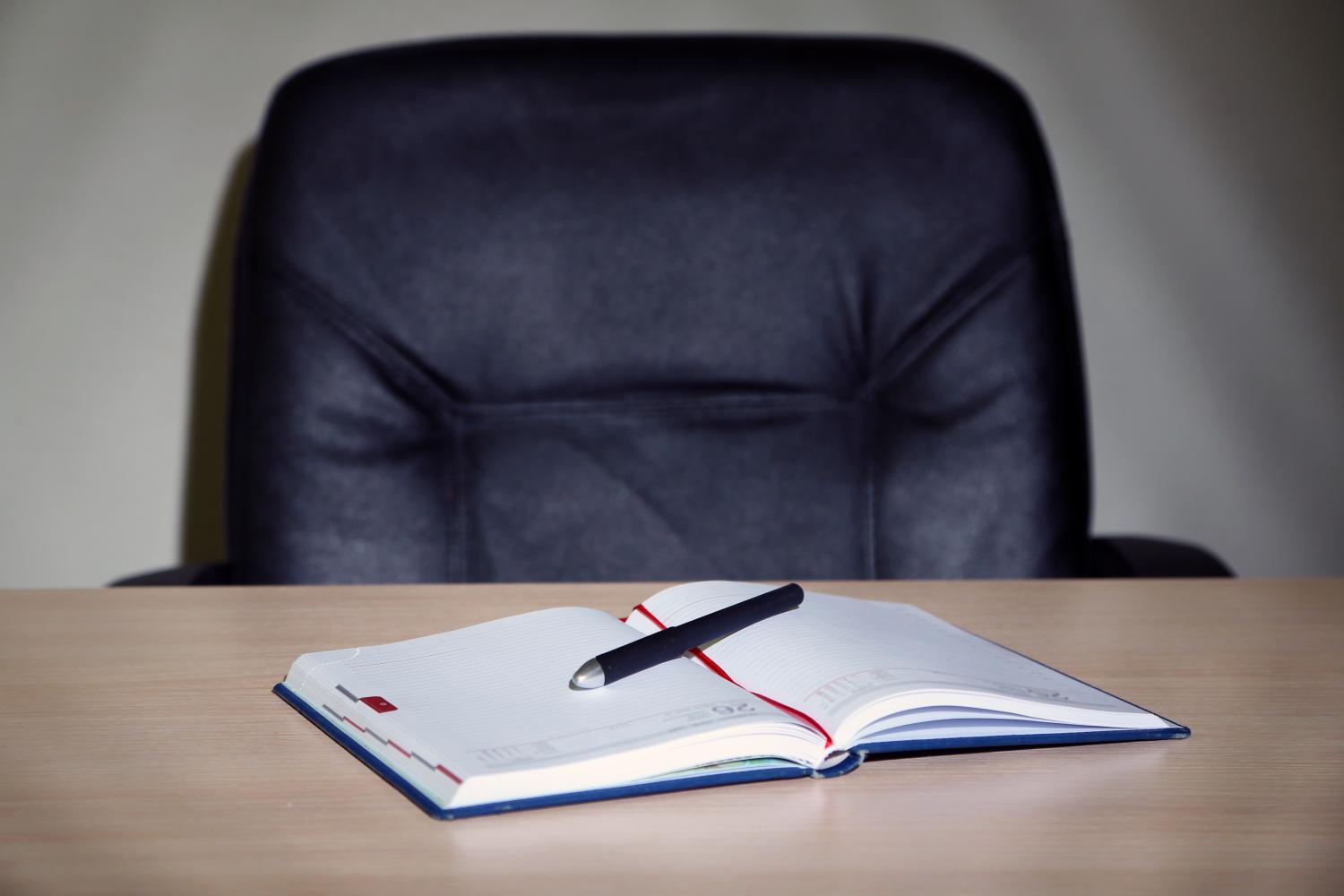 Empty office chair, notebook and pen