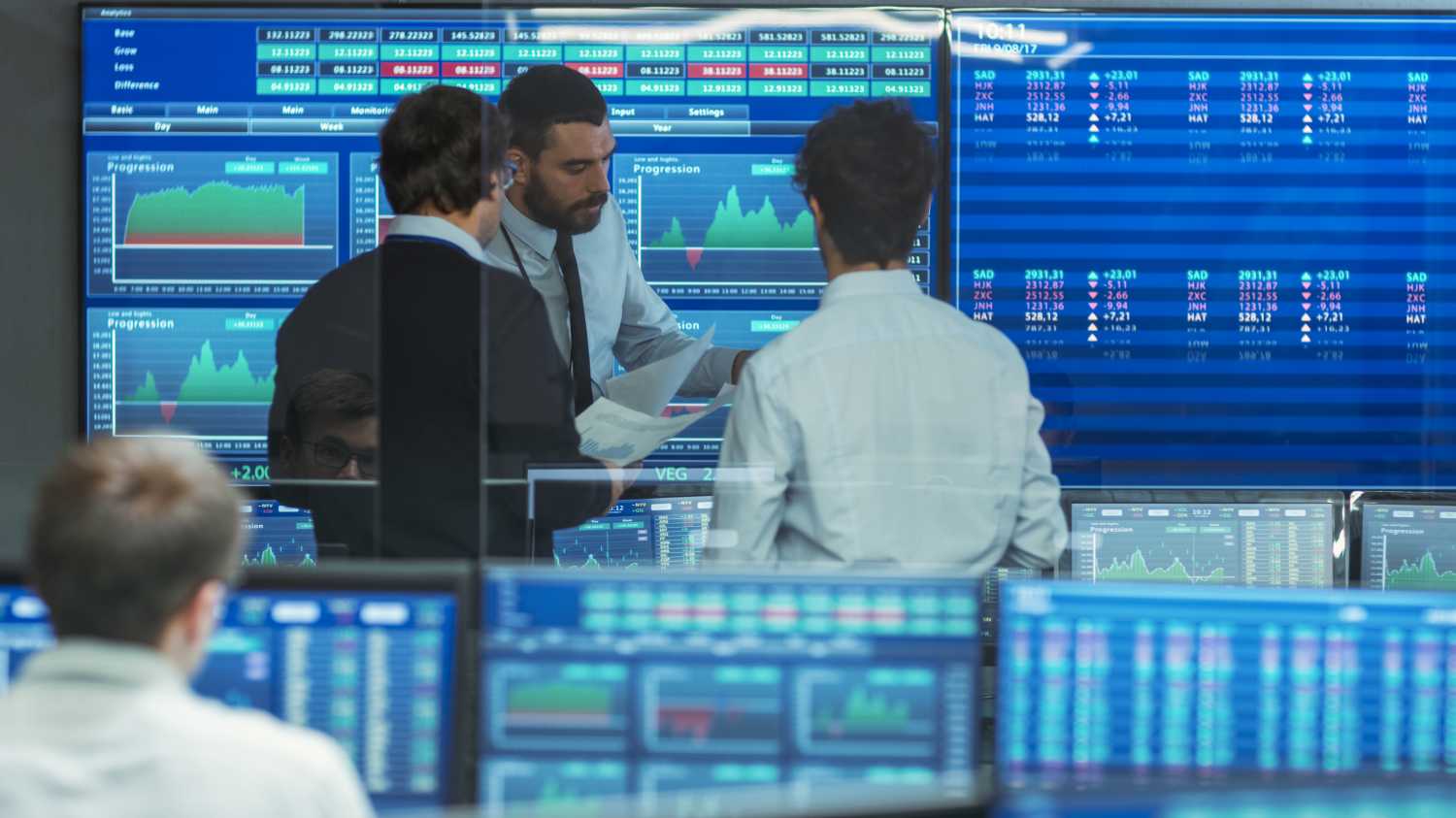Three Experienced Stock Traders Talking Business. They Work for a Big Stock Exchange Firm. Office is Full of Displays Showing Data, Infographics and Numbers.