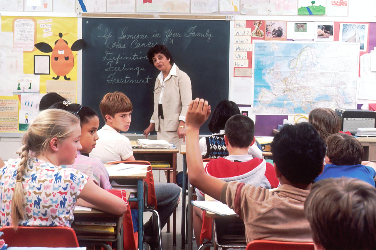 Teacher standing at the front of a classroom.