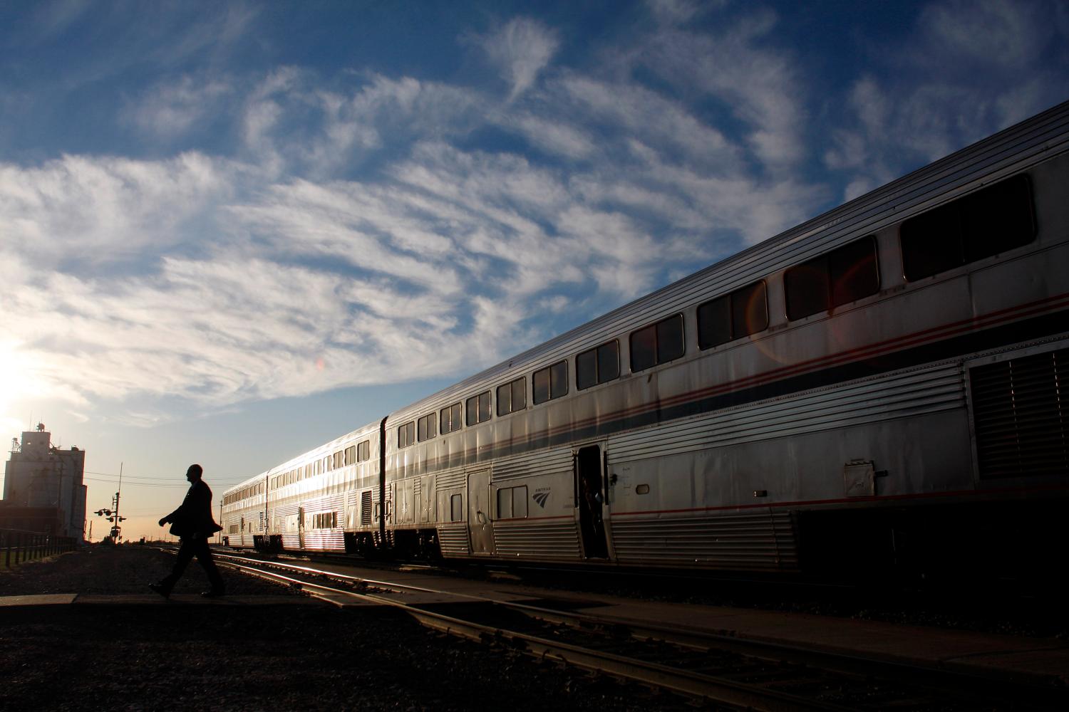 An Amtrak train attendant walks across the tracks at the Holdrege station after exiting the 5 California Zephyr Amtrak train in Holdrege, Nebraska June 13, 2008. U.S. government-owned passenger rail company Amtrak wields improper and coercive regulatory power over private freight carriers under a law that lets it help set rules that competing railroads must follow, a federal appeals court ruled on April 29, 2016.   REUTERS/Joshua Lott/File Photo