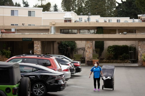 A worker carries a garbage can while wearing a mask at the Life Care Center of Kirkland, where two of three confirmed coronavirus cases in the state had links to the long-term care facility in Kirkland, Washington, U.S. March 1, 2020. REUTERS/David Ryder