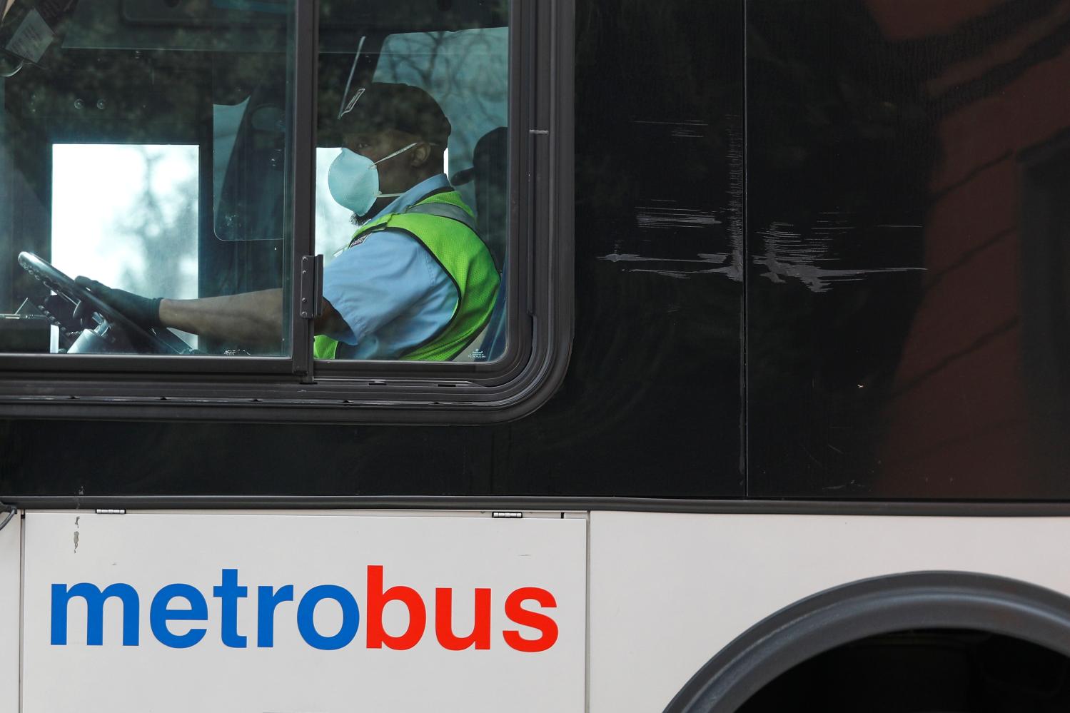 A Washington Metro bus driver passes along a route wearing a face mask, as Mayor Muriel Bowser issued a State of Emergency in response to the coronavirus disease (COVID-19) in Washington, U.S., March 20, 2020. REUTERS/Tom Brenner