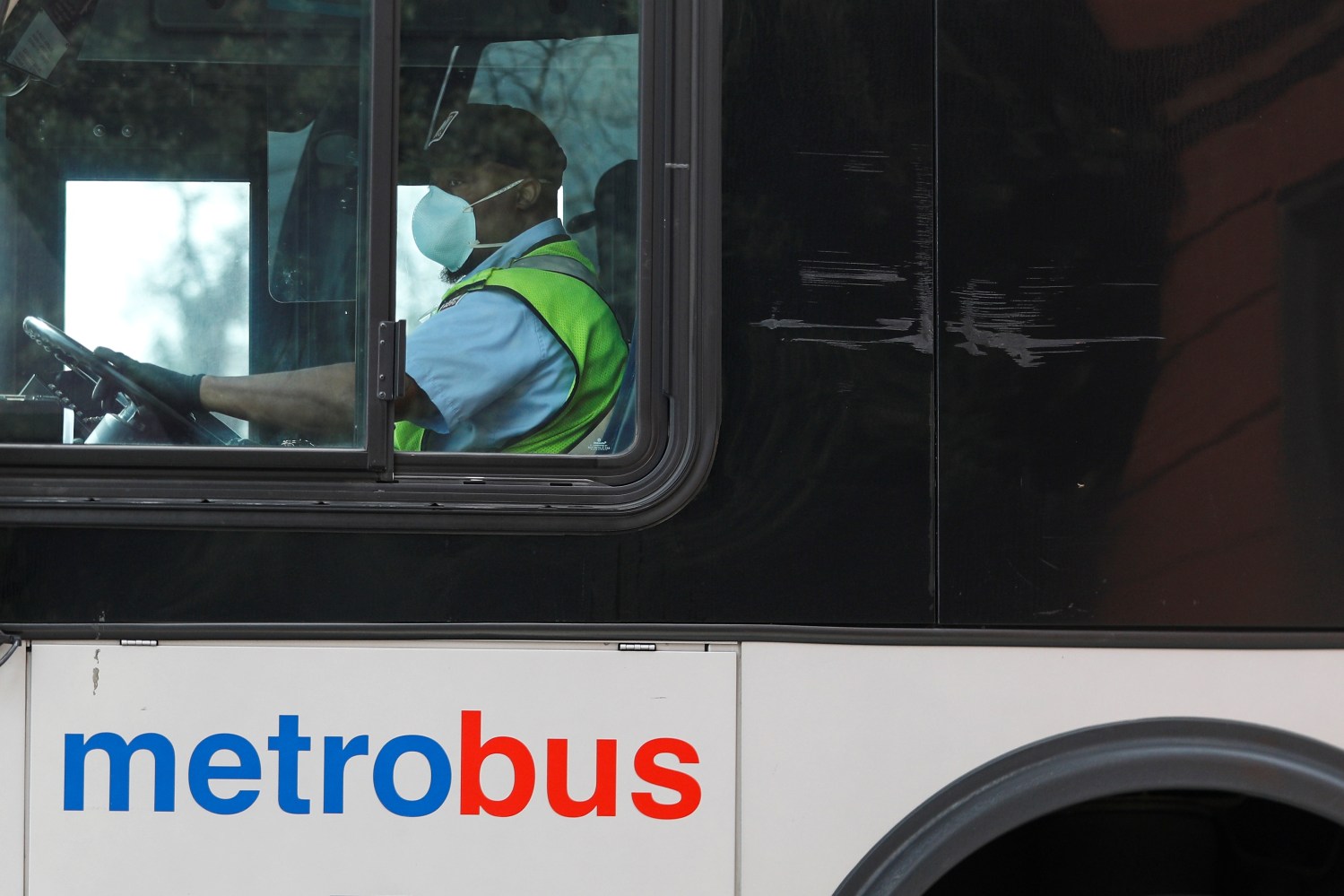 A Washington Metro bus driver passes along a route wearing a face mask, as Mayor Muriel Bowser issued a State of Emergency in response to the coronavirus disease (COVID-19) in Washington, U.S., March 20, 2020. REUTERS/Tom Brenner
