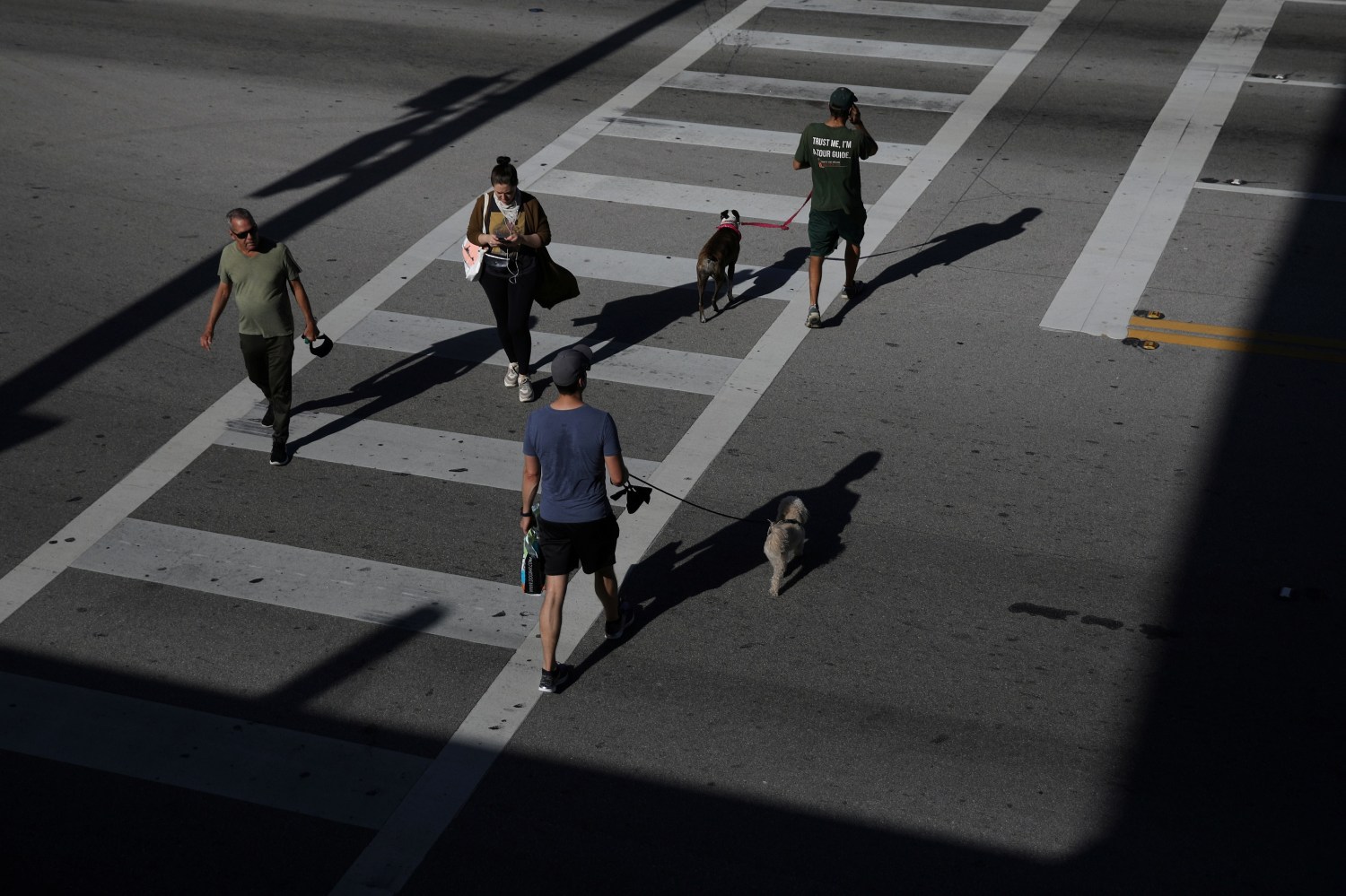 People walks cross a street practicing 'social distancing' at a commercial area of South Beach after local authorities restricted the activities of restaurants, bars, gyms, movie theaters and other similar businesses and rolled out a midnight curfew for precaution due to coronavirus disease (COVID-19) spread, in Miami Beach, Florida, U.S., March 20, 2020. REUTERS/Carlos Barria